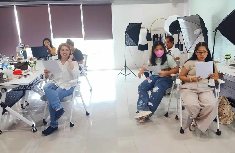 ผู้เข้าฝึกถือสคริปต์ซ้อมพูดในห้องที่มีไฟสตูดิโอ
